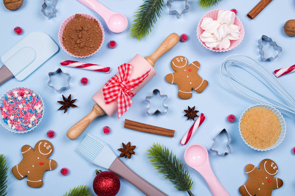 Ψήσιμο Χριστουγέννων μπισκότα κάρτα. Χριστούγεννα μπαχαρικά, κόπτες μπισκότων, συστατικά για ψήσιμο και κουζίνα σκεύη μελόψωμο μπισκότα Χριστουγέννων σε μπλε παστέλ φόντο  - Φωτογραφία, εικόνα