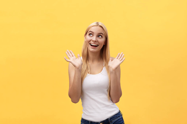 Surprised young woman wearing white clothes while looking at camera isolated on yellow background. - Photo, Image