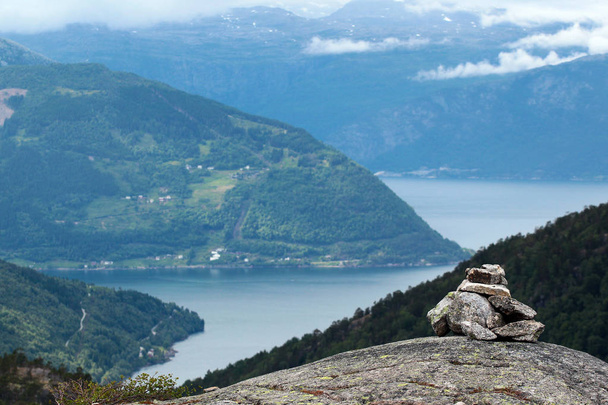 Stone cairn in Husedalen valley with cascade of four waterfalls, Kinsarvik, Norway - Photo, Image