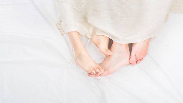 Feet of two couple sleeping on bed under blanket. Up view - Foto, imagen