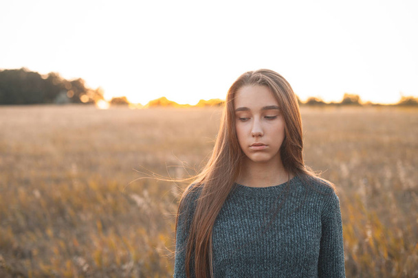 Calm young woman standing outdoors at sunset - Foto, immagini
