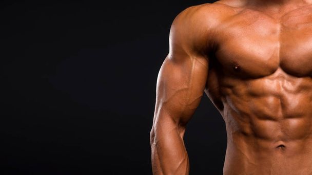 Low-key image of muscular masculine man over dark background. - Valokuva, kuva