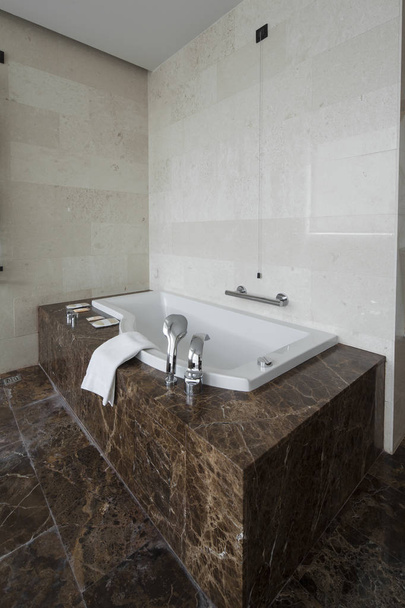 Moderno bagno interno con doppio lavabo e grandi specchi, vasca da bagno, piastrelle, finestra vista e asciugamani
. - Foto, immagini