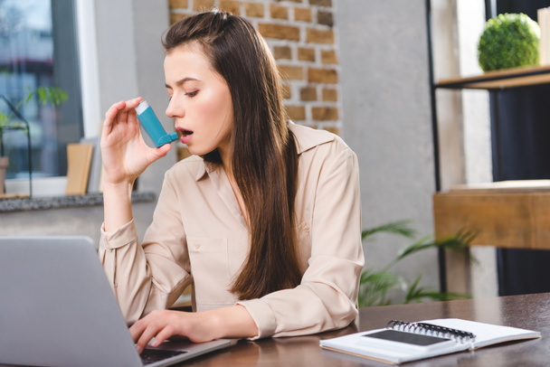 молодая бизнесвумен с астмой, использующая ингалятор в офисе
 - Фото, изображение