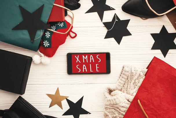 Christmas big sale text, xmas sign on phone screen. Special discount christmas offer. Phone with advertising message at money, wallet, bags, clothes, gift boxes, price tags. Shopping - Photo, image
