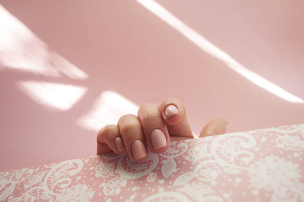 Рука молодої жінки з красивим манікюром на пастельно-рожевому тлі з копіспасом
. - Фото, зображення