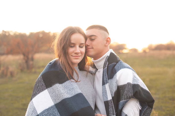 Молодая пара, покрытая одеялом, стоящая на поле
 - Фото, изображение