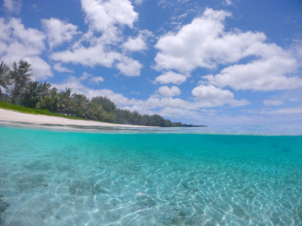 HALF UNDERWATER: Amazing glassy water splashes over camera filming empty tropical coast in sunny Cook Islands. Awesome shot of remote romantic beach and tranquil crystal clear ocean in the summer. - Photo, Image