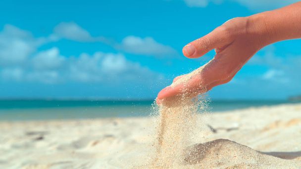 COPY SPACE, FECHAR UP: Pequenos grãos de areia branca são varridos da mão feminina pela brisa suave do verão. Mulher irreconhecível em férias brincando junto ao oceano recolhe um punhado de areia quente
. - Foto, Imagem
