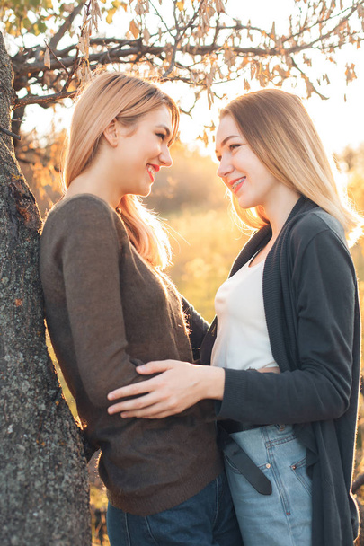 zwei fröhliche junge Frauen, die neben dem Baum stehen. beste Freunde - Foto, Bild