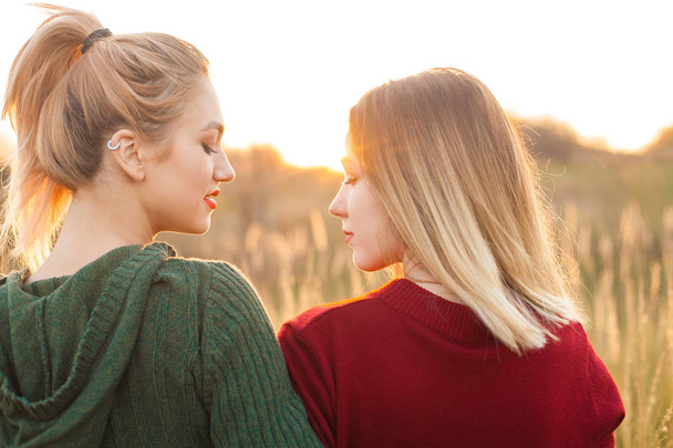 Kaksi iloista nuorta naista seisomassa kentällä auringonlaskun aikaan. Parhaat ystävät
 - Valokuva, kuva