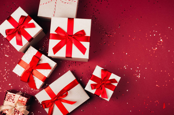 Many present boxes with red bow on red background - Foto, imagen