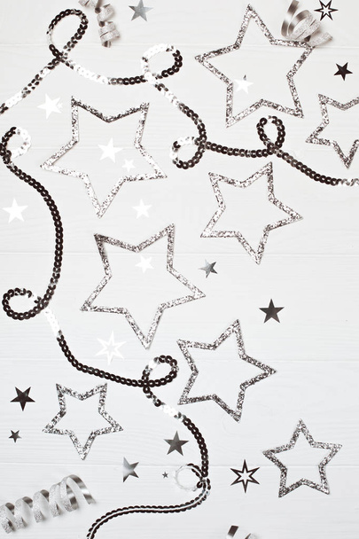 Silver sparkling stars with sequin chain on white wooden background. - Фото, изображение