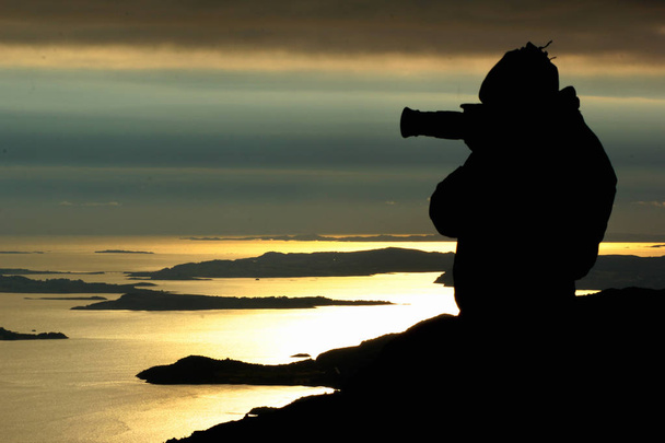 Silhouette eines Fotografen beim Blick auf den Sonnenuntergang in der Nähe von Preikestolen, Norwegen - Foto, Bild