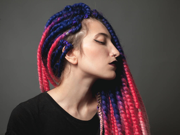 Woman with color braids on the gray background. Close up. Profile - 写真・画像