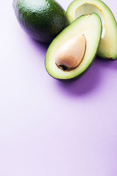Avocado is whole and cut on a pink background with copy space - Fotografie, Obrázek