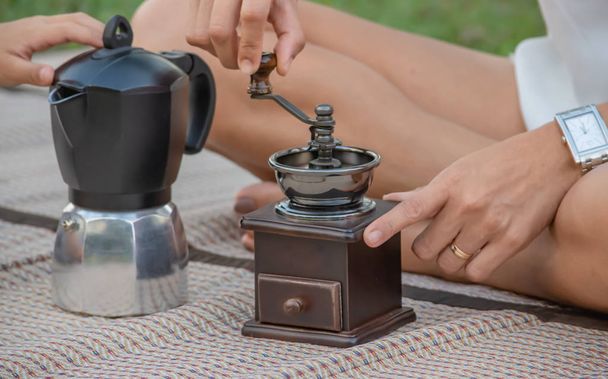 Hand rotating grinding coffee beans and the coffee pot is placed on the mat. - Foto, imagen
