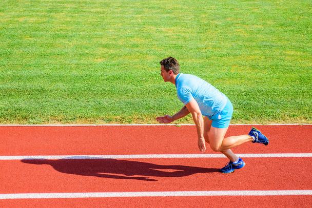 Man athlete runner push off starting position stadium path sunny day. Runner sprint race at stadium. Runner captured in motion just after start of race. How to start running. Boost speed concept - Photo, Image
