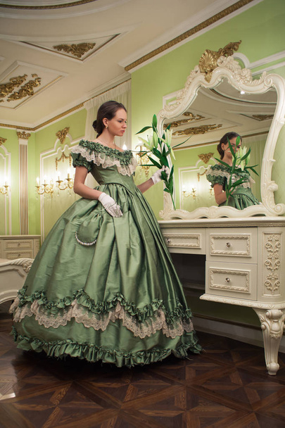 Portrait of retro baroque fashion woman wearing green vintage dress at old palace interior - Photo, Image
