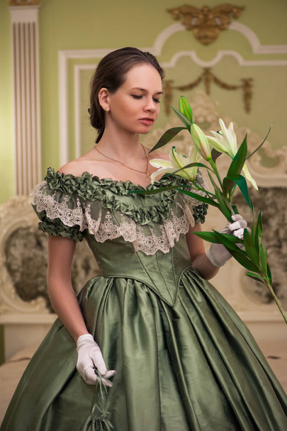 Portrait of retro baroque fashion woman wearing green vintage dress at old palace interior - Foto, Imagen
