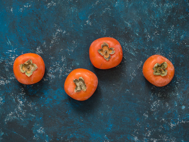 Ripe orange fig persimmon fruit on a blue grunge background. Flat lay. Top view. Copy space - Foto, Bild
