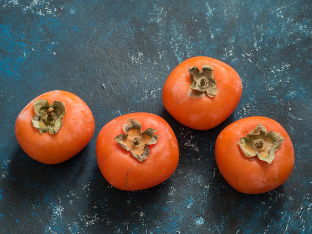 Ripe orange fig persimmon fruit on a blue grunge background. Flat lay. Top view. Copy space - Photo, image