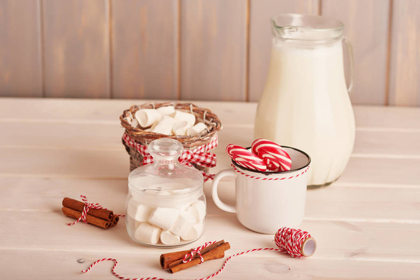 Новогодние сладости зефир, леденцы и молоко на столе с подарками
 - Фото, изображение