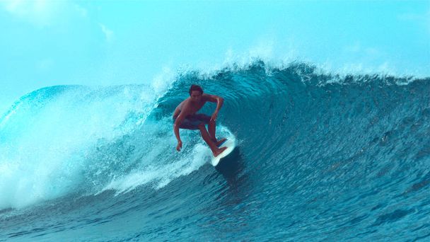 Közelről: Extrém surfboarder lovagol egy epikus smaragd színű hordó hullám napos Teahupoo, Tahiti. Fiatal profi szörfös, szórakozás a epikus kristálytiszta cső hullám meglovaglása lenyűgöző Francia Polinézia. - Fotó, kép