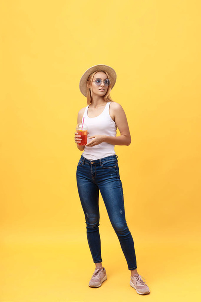 Full length portrait of a cheerful young woman wearing summer clothes while posing and looking at camera isolated over yellow summer background - Photo, Image