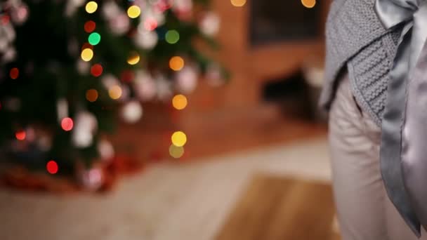 Giovane ragazza che dà un regalo di Natale allungando il braccio - primo piano sulle mani, albero di Natale sfocato sullo sfondo
 - Filmati, video