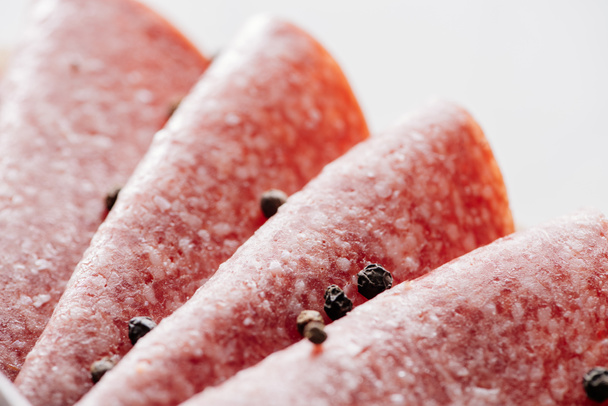Close-up van verpakte stukken van heerlijke gesneden salami met peper  - Foto, afbeelding