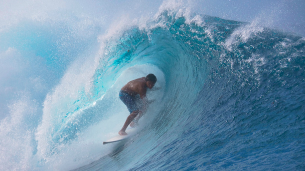hautnah: Die perfekte Barrel-Welle sprüht kristallklares Meerwasser über den Extremsportler, der in Tahiti surft. Furchtloser junger männlicher Surfer, der seinen Urlaub mit großen türkisfarbenen Röhrenwellen verbringt. - Foto, Bild