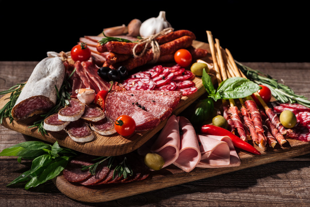 cutting boards with delicious salami, smoked sausages, ham and vegetables on wooden rustic table - 写真・画像
