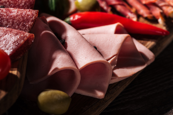 close up view of wooden cutting board with tasty sliced ham and vegetables - Foto, Imagem