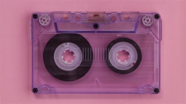Retro muziek compacte cassettebandje afgehaspeld alsof spelen, op roze achtergrond - stop motion animatie - Video