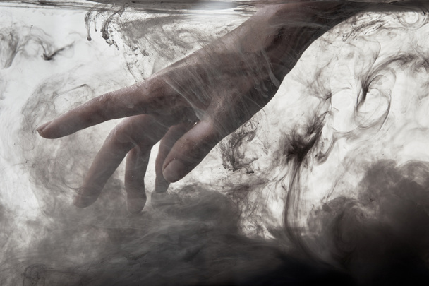 mano femenina en agua con pintura gris
 - Foto, Imagen