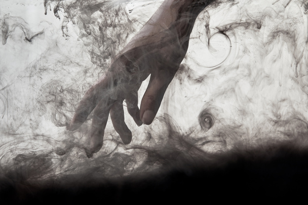female hand in water with swirls of black paint - Fotoğraf, Görsel
