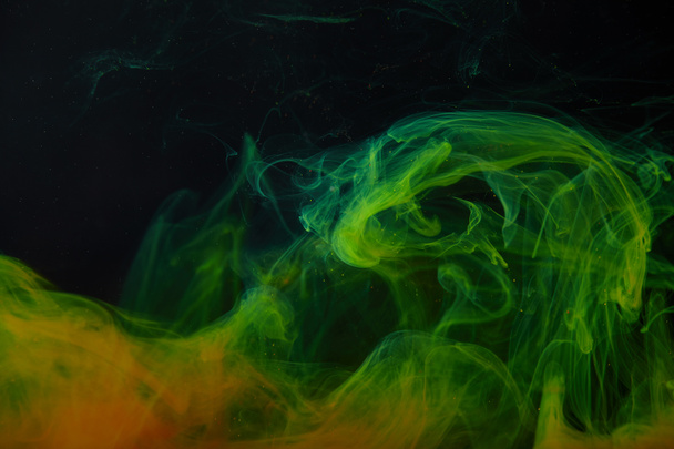 dark background with abstract green and orange swirls of paint  - Zdjęcie, obraz