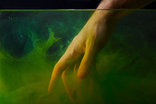 hand in water with green smoky swirls - Foto, Imagen