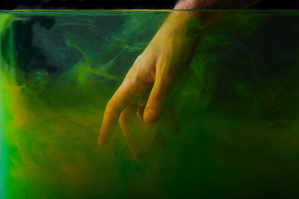 緑色のペンキが付いている水に手を入れて男のビューをトリミング  - 写真・画像