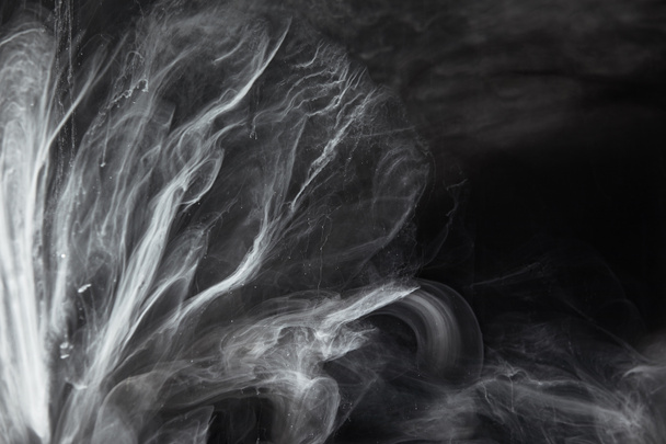 abstract flowing swirls of grey paint on black background - Foto, imagen