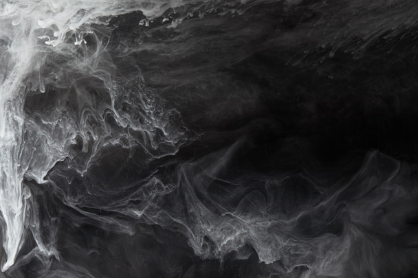 abstract flowing swirls of grey paint on black background - Photo, Image