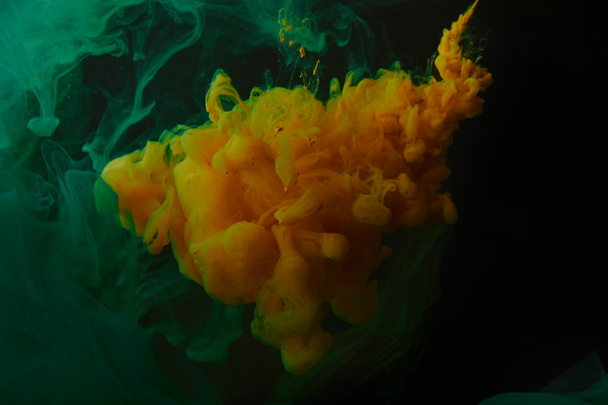 creative background with green and orange swirls of paint in water - Valokuva, kuva