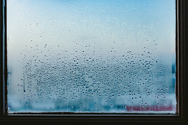 Ισχυρή υγρασία το χειμώνα. Σταγόνες νερού από σπίτι συμπύκνωση σε ένα παράθυρο. Η ΕΘΝΙΚΗ ΚΟΜΨΗ γυαλί φόντο - Φωτογραφία, εικόνα