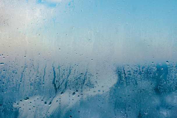 Sterke vochtigheid in de winter. Water drops vanaf huis condensatie op een venster. Beneveld glas achtergrond - Foto, afbeelding
