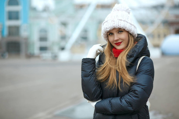 Stylish blonde woman with red lipstick wearing knitted cap, enjoying city walk. Space for text - Photo, Image