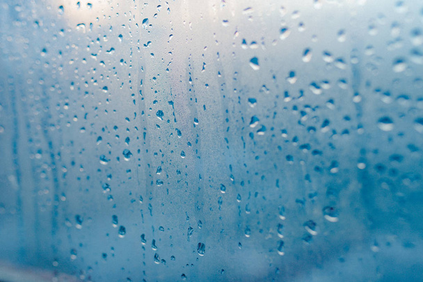 starke Luftfeuchtigkeit im Winter. Wasser tropft aus dem Hauskondenswasser auf ein Fenster. vernebelter Glashintergrund - Foto, Bild