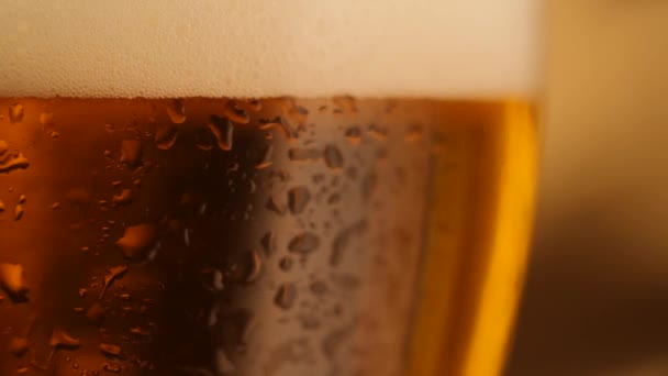 Detalle de chupito de cerveza fresca giratoria con gotas sobre vidrio
 - Metraje, vídeo