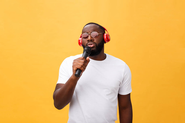 若いアフリカ系アメリカ人の男は身に着けているヘッドフォンとイエローゴールドで音楽を楽しむ背景. - 写真・画像