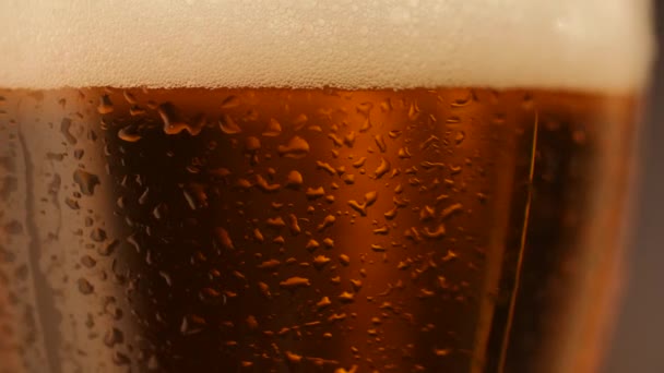 Detail schot van roterende fris biertje met druppels op glas - Video